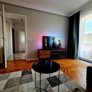 a living room with a flat screen tv and a stool at Campia Turzii central apartment in Cîmpia Turzii