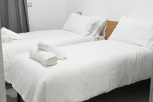 2 bedden in een kamer met witte lakens en kussens bij Casa karas in Milaan