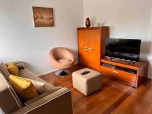 a living room with a couch and a tv and a chair at Apartamento Vitória in Praia da Vitória
