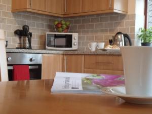 a kitchen with a wooden table with a microwave at Alpine Park Cottages in Aylesbeare