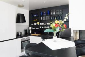 a black and white kitchen with a vase of flowers on a table at EXIGEHOME-Maison avec piscine et tennis à 30 min de Paris in Saint-Gratien