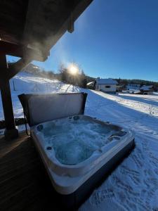 Chalet Mayen, luxueux et intimiste في Ban-sur-Meurthe-Clefcy: حوض استحمام ساخن جالس على شرفة في الثلج