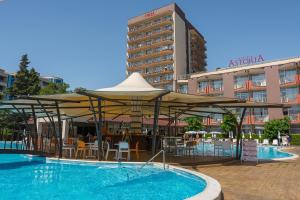 a swimming pool with tables and umbrellas next to a hotel at MPM Astoria Hotel - Ultra All Inclusive in Sunny Beach