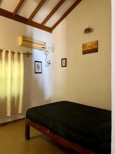 ein Schlafzimmer mit einem schwarzen Bett in einem Zimmer in der Unterkunft The Sunset Chalet! in Anjuna