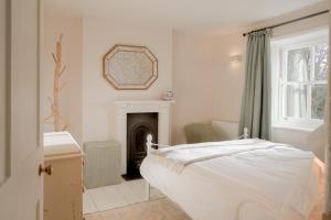een witte slaapkamer met een bed en een open haard bij The Villa in Coberley - Stylish 3BD with Garden! 