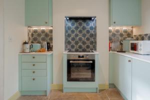 a kitchen with blue cabinets and a stove at The Villa in Coberley - Stylish 3BD with Garden! 