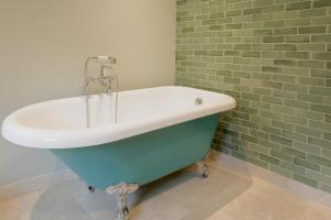 a bath tub in a bathroom with a brick wall at The Villa in Coberley - Stylish 3BD with Garden! 
