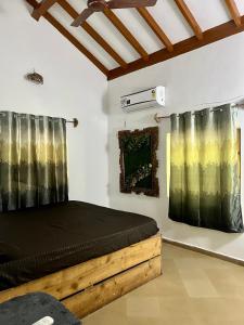 a bedroom with a bed with black sheets and curtains at The Sunset Chalet! in Anjuna