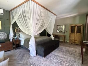 a bedroom with a canopy bed with white curtains at Green Elephant in Lilongwe