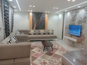 een woonkamer met een bank en een tv bij لاصحاب التميز شقة راقية في المهندسين بالقرب من جامعة الدول والنيل in Caïro