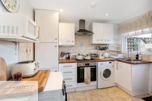 cocina con armarios blancos, lavadora y secadora en Bohemian Haven Guesthouse en Oxford