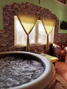 Sunny Side Fruska Gora -touristic estate في Velika Remeta: حوض استحمام كبير في غرفة معيشة مع نافذتين