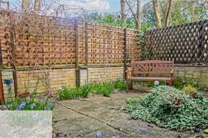 a wooden fence with a bench in a garden at Bohemian Haven Guesthouse in Oxford