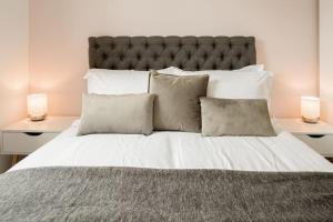 a large bed with white sheets and two lamps at Stunning 2 Bed with Private Patio and Free Parking in Cheltenham