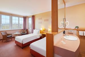 a hotel room with two beds and a sink at Lindner Hotel Wiesensee in Westerburg