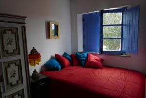 a bedroom with a red bed and a window at Barranco do Zambujeiro in Vila do Bispo