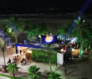 un groupe de personnes debout à l'extérieur d'un bâtiment la nuit dans l'établissement A melhor localização da PG. Com ar cond.!, à Praia Grande