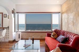 Sala de estar con sofá rojo y vistas al océano en El Mar y Tú, en Arrieta