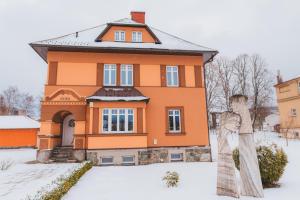 una estatua frente a una casa en la nieve en Kavárna a penzion REICHL, en Králíky