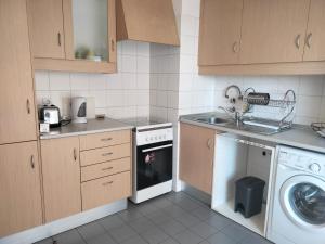 a kitchen with a washing machine and a dishwasher at Ap Central Chic in Odivelas
