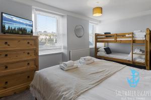 a bedroom with two bunk beds with towels on a bed at Coastal View Cottage in Torquay