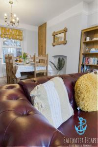 - un canapé en cuir brun dans le salon dans l'établissement Coastal View Cottage, à Torquay