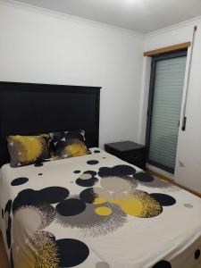 um quarto com uma cama com um edredão preto e amarelo em Ap Central Chic em Odivelas