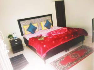 een slaapkamer met een groot rood bed met blauwe kussens bij evergreen family homesty in Agra