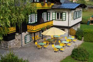 un patio al aire libre con mesas, sillas y una sombrilla en Hotel Harrida, en Weissensee