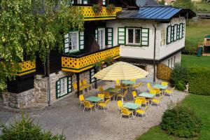 an outdoor patio with tables and chairs and an umbrella at Hotel Harrida in Weissensee