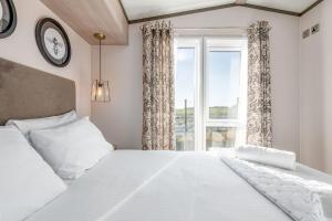 a bedroom with a large white bed and a window at Lodge No 9 - St Andrews Lodge Park in Strathkinness