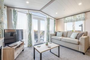 a living room with a couch and a tv at Lodge No 9 - St Andrews Lodge Park in Strathkinness