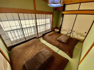 two beds in a small room with two windows at 貸切御宿　憩（Ikoi）/ Nikko Kinugawa Area in Imaichi
