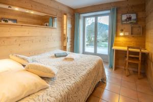 1 dormitorio con cama, escritorio y ventana en Arcanson, en Méaudre