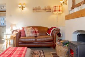 un sofá de cuero marrón en la sala de estar en Jasmine Cottage - 2 Bedroom in Heart of Bourton! en Bourton on the Water