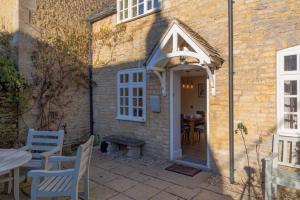 a stone house with an open door and a table and chairs at Jasmine Cottage - 2 Bedroom in Heart of Bourton! in Bourton on the Water