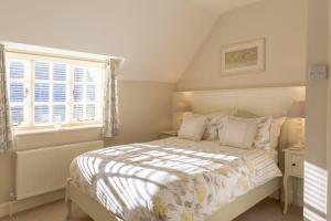 1 dormitorio con cama y ventana en Jasmine Cottage - 2 Bedroom in Heart of Bourton! en Bourton on the Water