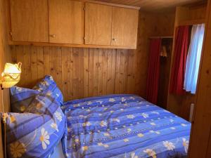 een slaapkamer met een bed met een blauw dekbed bij Chalet Alphütte in Rosswald