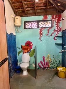 a bathroom with a toilet with a painting on the wall at The Wild Flower! in Anjuna