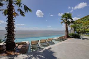 uma piscina com cadeiras e palmeiras junto ao oceano em DoubleTree by Hilton Porto Alegre em Porto Alegre