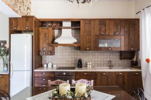 uma cozinha com armários de madeira, uma mesa e um frigorífico em Casa di campagna em Faskomiliá
