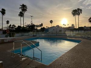 uma grande piscina com um pôr-do-sol ao fundo em Relaxing Bungalow Playa del Inglés em Maspalomas