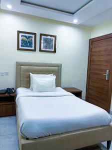 a bedroom with a large white bed and a wooden door at Plush Hotel,Abuja in Abuja