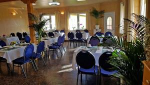uma sala de jantar com mesas e cadeiras com cadeiras azuis em Pension ZUM LINDENWALD Colbitz em Colbitz