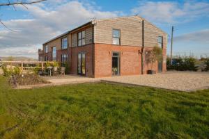 une maison en briques avec une pelouse devant elle dans l'établissement Discovery Barn - Luxury 2 Bed Barn Conversion!, à Cropthorne