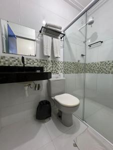 uma casa de banho branca com um WC e uma cabina de duche em vidro. em Mais Hotel Express em São Luís