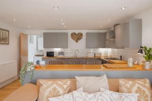 een woonkamer met een bank en een keuken bij Discovery Barn - Luxury 2 Bed Barn Conversion! in Cropthorne