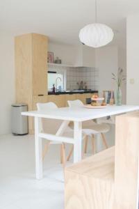 a white kitchen with a white table and chairs at Boshuisje op de Veluwe met sfeervolle tuinkas in Putten