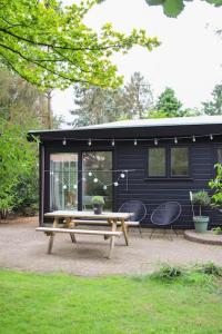 a black tiny house with a picnic table and chairs at Boshuisje op de Veluwe met sfeervolle tuinkas in Putten