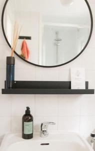 a bathroom sink with a mirror and a bottle of soap at Boshuisje op de Veluwe met sfeervolle tuinkas in Putten